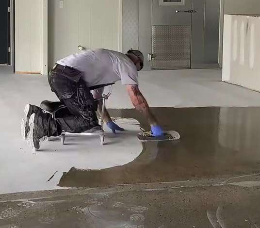 Pracownik łatający dziury w posadzce betonowej